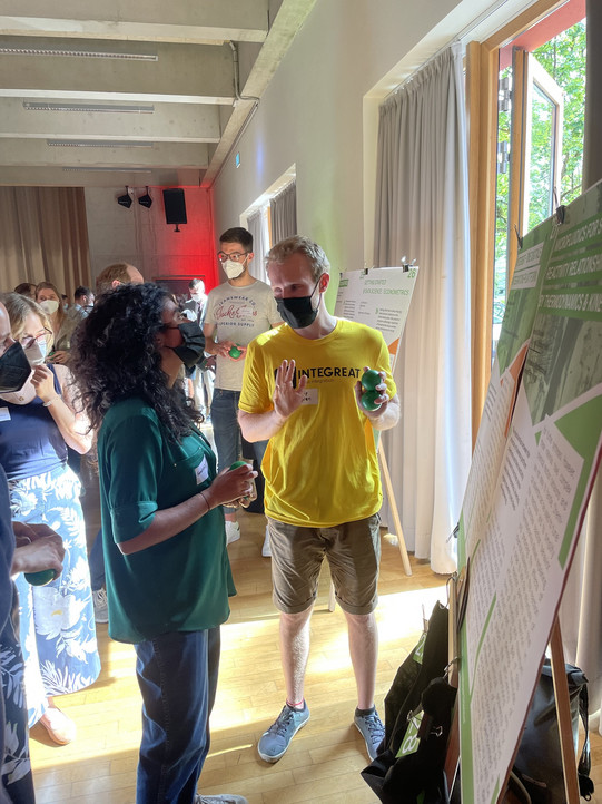 Foto von Philip Popien, der einer anderen person ein Poster erklärt