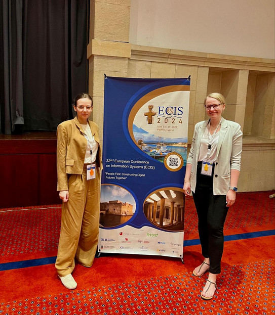 Lisa Schned and Dr. Lisa Gussek next to a poster of the conference