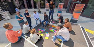Mehrere Personen sitzen um ihre Notizen bei einem Kreativworkshop