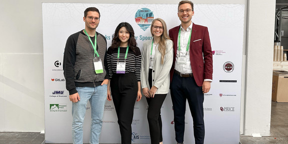 4 Doktorand*innen vor Poster Wand der ICIS 2022 Konferenz